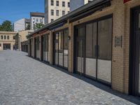 the sidewalk is paved with stones and has a bench in front of it, with no people inside