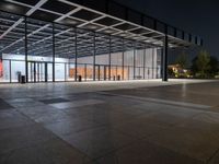 an empty plaza at night lit by low lights and an open walkway with a large window