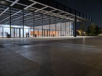 an empty plaza at night lit by low lights and an open walkway with a large window