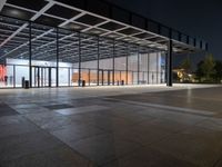 an empty plaza at night lit by low lights and an open walkway with a large window