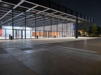 an empty plaza at night lit by low lights and an open walkway with a large window