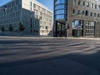 a cross walk next to a building on the side of a street with the reflection of a building on the ground