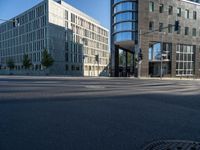 a cross walk next to a building on the side of a street with the reflection of a building on the ground