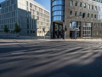 a cross walk next to a building on the side of a street with the reflection of a building on the ground