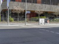 a person is crossing a street in front of an office building with graffiti on the wall and trees