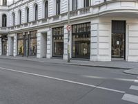 an empty city street with many stores on the corner and a man walking down the street next to it