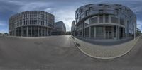 a round building sits in a parking lot with curved concrete sides on both sides with windows and some of them showing various angles