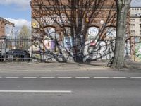 a motorcycle is parked on the side of the road beside a gate covered in graffiti