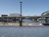 the walkway on the banks of the river, and the city in the background is very tall, with a bridge