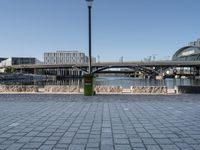 the walkway on the banks of the river, and the city in the background is very tall, with a bridge