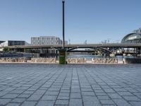 the walkway on the banks of the river, and the city in the background is very tall, with a bridge