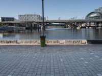 the walkway on the banks of the river, and the city in the background is very tall, with a bridge