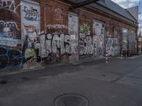 a corner with a wall covered in graffiti, a sidewalk sign, and a manhole