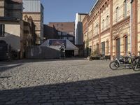 some bicycles parked on the street outside a building in an alleyway with other buildings