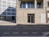 a building with a graffiti on it in a town street with buildings in the background