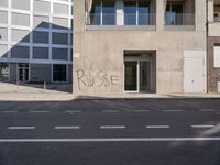 a building with a graffiti on it in a town street with buildings in the background