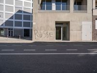 a building with a graffiti on it in a town street with buildings in the background