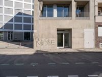 a building with a graffiti on it in a town street with buildings in the background