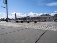 a stone pavement that is near a waterway in a city area with boats docked and buildings in the distance