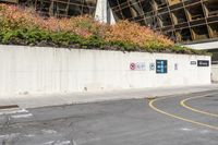 a large white wall next to a road with traffic signs on it that read no parking