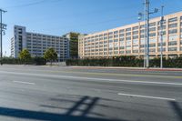 a empty street in front of a large building with balconies and bushes and other residential buildings