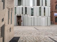 a small dog is walking down an empty sidewalk in front of a building with shuttered glass on it