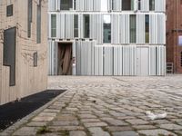 a small dog is walking down an empty sidewalk in front of a building with shuttered glass on it