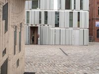 a small dog is walking down an empty sidewalk in front of a building with shuttered glass on it