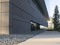 a building with a long walkway next to a small field of rocks in front of it