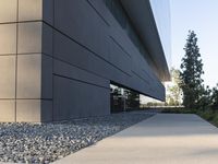 a building with a long walkway next to a small field of rocks in front of it