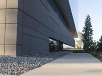 a building with a long walkway next to a small field of rocks in front of it