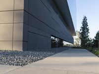 a building with a long walkway next to a small field of rocks in front of it