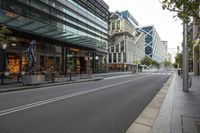 the empty street of an urban city with tall buildings and benches on both sides of the road