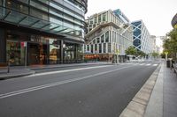 the empty street of an urban city with tall buildings and benches on both sides of the road