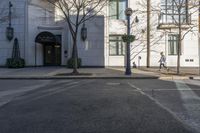 a couple walk past the entrance to a building that has a parking meter sitting next to it