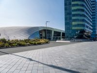 large modern glass building sitting across the street from the curved glass wall of an office