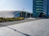 large modern glass building sitting across the street from the curved glass wall of an office