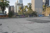 many buildings are in the background near graffiti covered parking lot's and there is graffiti on the ground