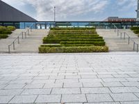 a photo of stairs and shrubbery outside of an empty building on a cloudy day