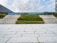 a photo of stairs and shrubbery outside of an empty building on a cloudy day