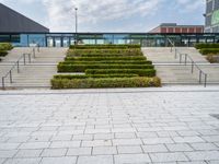 a photo of stairs and shrubbery outside of an empty building on a cloudy day