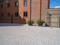 large brick yard that is on the ground and surrounded by windows and a lot of pots