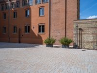 large brick yard that is on the ground and surrounded by windows and a lot of pots