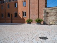 large brick yard that is on the ground and surrounded by windows and a lot of pots