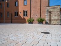 large brick yard that is on the ground and surrounded by windows and a lot of pots