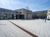 a white brick road in front of a brick building with a metal drain in the middle