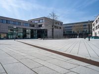 a white brick road in front of a brick building with a metal drain in the middle