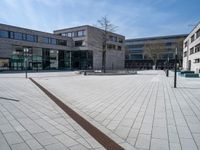 a white brick road in front of a brick building with a metal drain in the middle