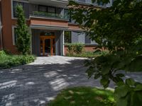 a residential driveway with a bench and bushes in between buildings and green grass on either side