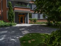 a residential driveway with a bench and bushes in between buildings and green grass on either side